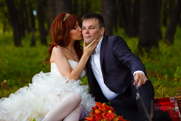 Couple bride and groom sitting on green grass, a picnic in woods — Stock Photo, Image
