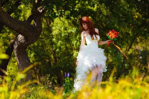 Samotna kobieta w białej sukni ślubnej panny młodej jest drzewo w lesie zielony — Zdjęcie stockowe
