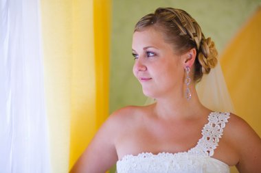 Gelin sarışın kadın standları ve pencereden dışarı büyük bir portre görünüyor