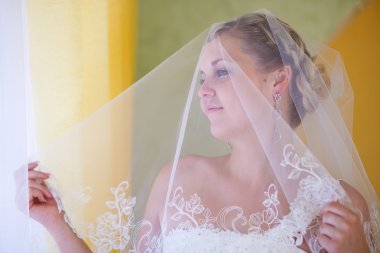 Gelini kadın sarışın indirdi örtü örtü ile standları ve dışarı bakar