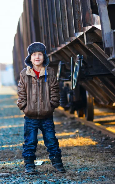 Jongen dakloze bum in een bruine jas en een bont hoed en verfrommeld je — Stockfoto