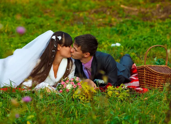 Bride and groom on a picnic in autumn are couple kissing on gree — Stock Photo, Image
