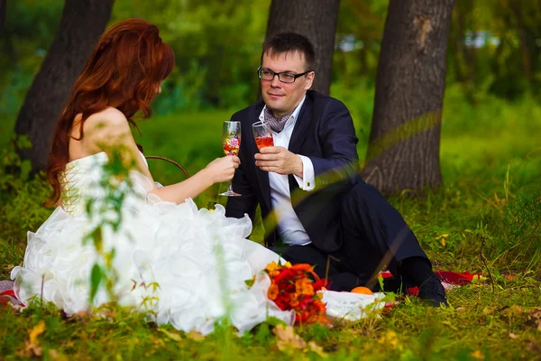 Bride redhead and groom at wedding in green field sitting on pic — Stock Photo, Image