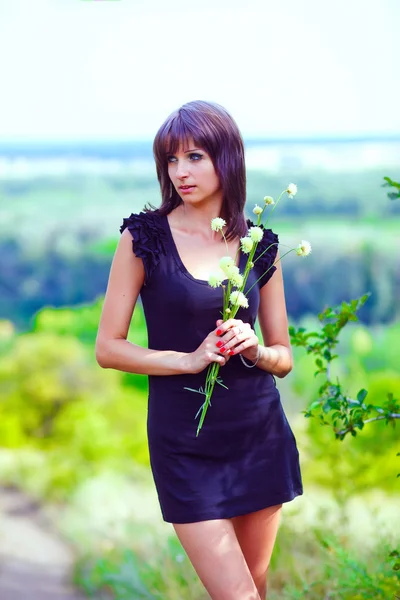 Morena fina retrato mulher segurando flores no verde campo aberto — Fotografia de Stock