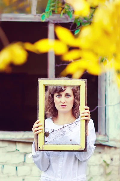 Mujer joven europea en vestido blanco sosteniendo una ventana de marco — Foto de Stock