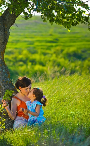 Mãe, filha, mulher e criança sentados na grama verde nea — Fotografia de Stock