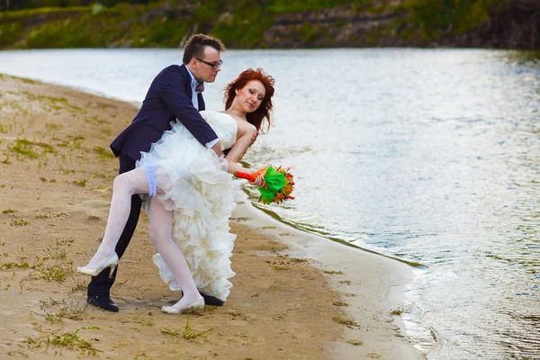 Novomanželé jsou na pláži u řeky, nevěsta — Stock fotografie