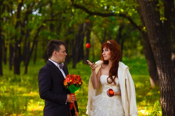 De bruid en bruidegom zijn in het groene bos, de vrouw gooit een — Stockfoto