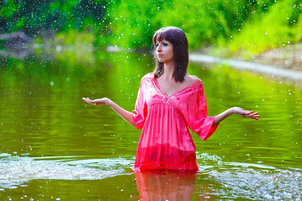 Woman in a red dress is standing in the rain to the waist in wat — Stock Photo, Image
