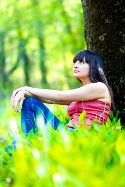 Beautiful brunette woman in jeans and a t-shirt sitting next to — Stock Photo, Image