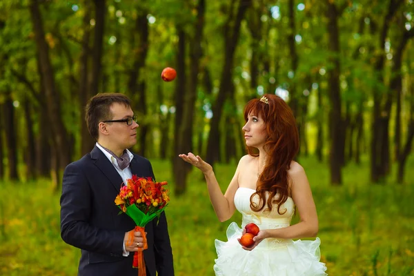 Bride and groom standing on green background in forest, red hair — Stock Photo, Image