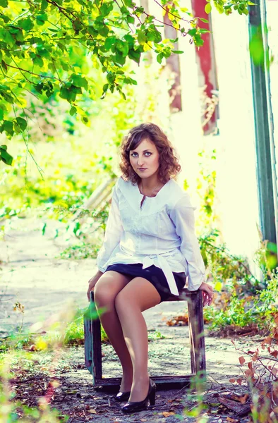 Curly girl woman sitting box next to abandoned building house ar — Stock Photo, Image