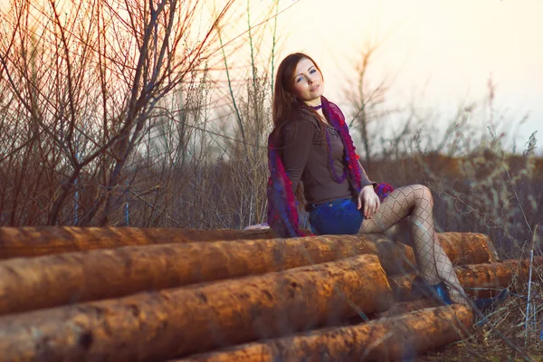 Brunette vrouw meisje zitten buiten op groep logs van hout pla — Stockfoto