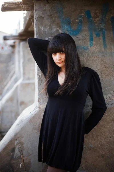 Witch girl brunette in a black dress against the wall — Stock Photo, Image