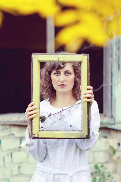 Joven mujer europea chica en vestido blanco sosteniendo marco ventana wi — Foto de Stock