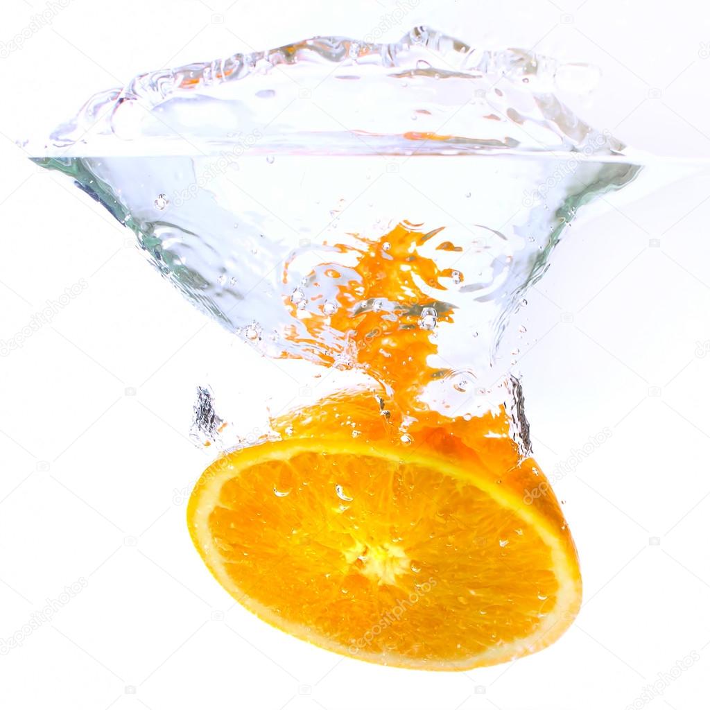 orange falls into the water covered with splashes and bubbles