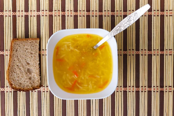 Sopa de tazón con una cuchara y pan en la estera — Foto de Stock