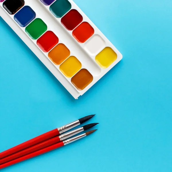 Brushes watercolors paints for children on blue background — Stock Photo, Image