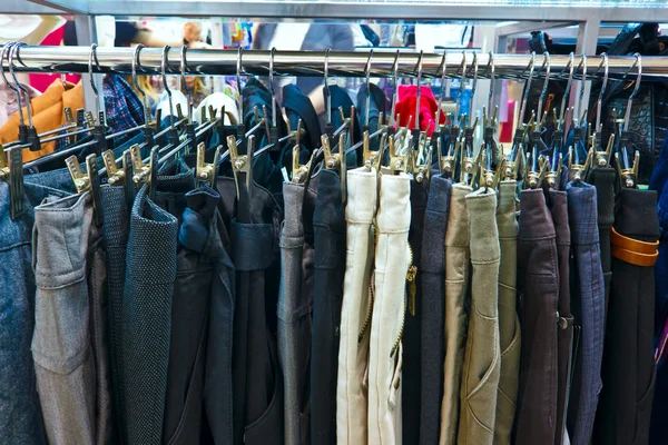Skupina různých barevné džíny visí na věšáku v úložišti — Stock fotografie