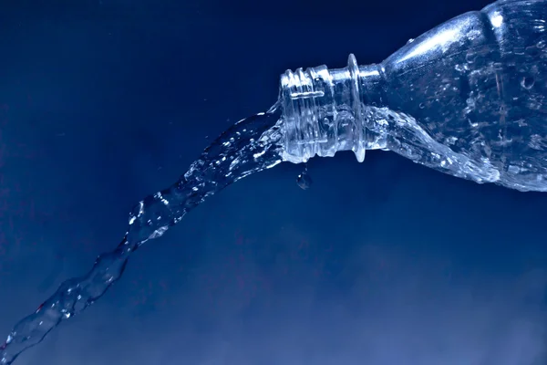 Éclaboussure d'eau de la bouteille sur la texture bleue avec pulvérisation — Photo