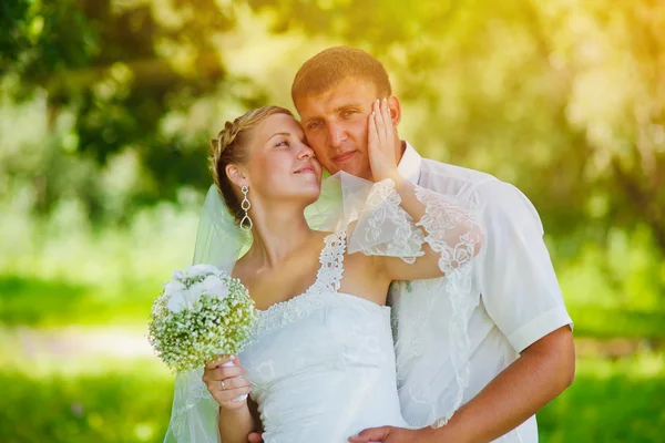 Luz do sol noiva loira noivo recém-casados de pé em uma floresta verde — Fotografia de Stock