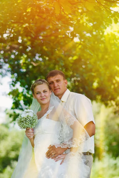 Solljus bruden brudgummen nygifta blondin stående i en grön skog — Stockfoto