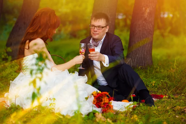 Sunlight bride redhead and groom at wedding in green field sitti — Stock Photo, Image