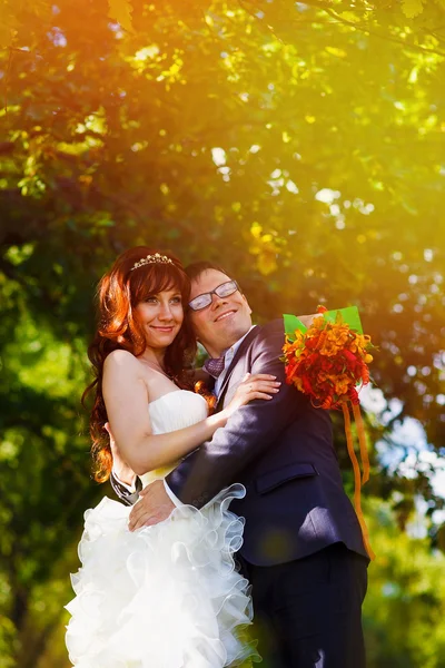 Sunlight Redhead bride and groom with glasses in a green forest — Stock Photo, Image