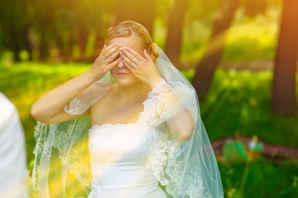 Sunlight bride woman has closed eyes with his hands for a surpri — Stock Photo, Image