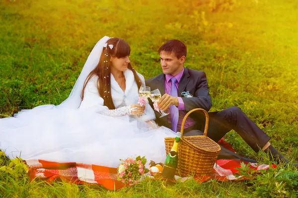 Sunlight bride and groom at wedding in green field sitting on pi — Stock Photo, Image