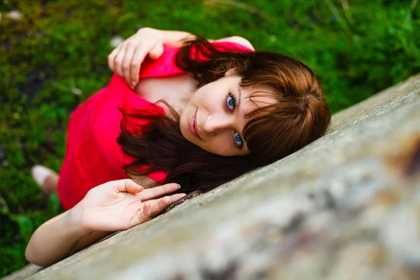 Ojos azules morena chica en un vestido rojo sobre fondo verde superior —  Fotos de Stock