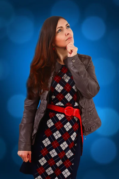 Brunette girl in a dress cage and fall leather jacket is th — Stock Photo, Image