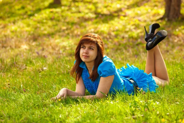Jonge brunette vrouw liggen op natuur groene gras in een blu — Stockfoto
