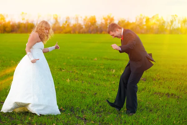 Bride and groom sunlight dancing merrily in green field, couple, — Stock Photo, Image