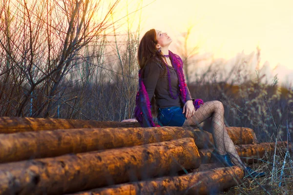 Bruneta sluneční dívka sedící žena venku v skupiny dřeva p — Stock fotografie