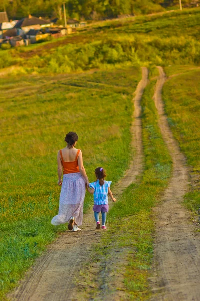 Little girl mother woman my daughter go on rural road through gr — Stock Photo, Image