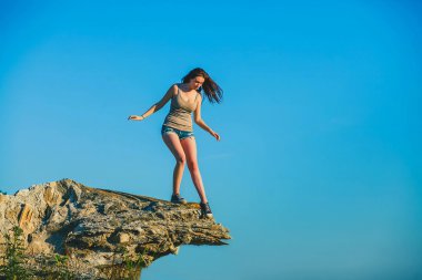 Acrophobia woman tall stands on top of a rock cliff edge and is