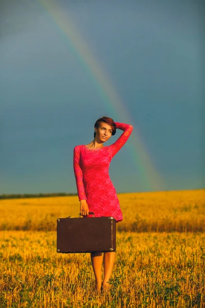 Hermosa joven en un vestido rosa sosteniendo maleta retro — Foto de Stock