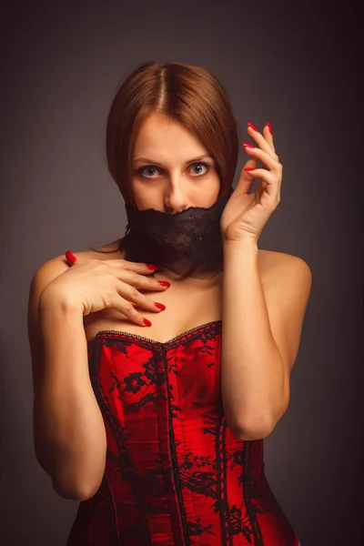 Woman girl in red corset, her mouth covered with bandage