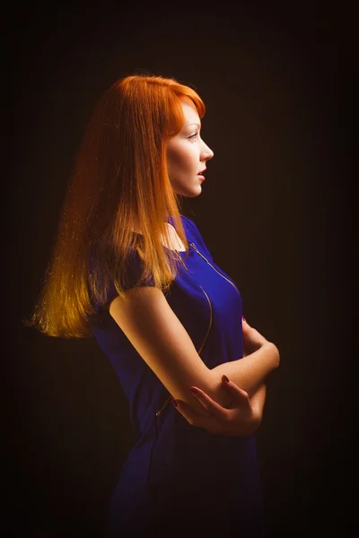Menina bonita ruiva mulher está olhando para longe em um azul escuro d — Fotografia de Stock