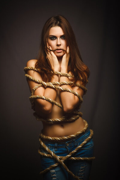 Brunette woman bound with rope prisoner in jeans