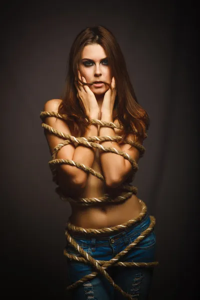 Brunette woman bound with rope prisoner in jeans — Stock Photo, Image