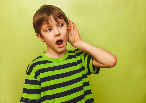 Baby teenager boy listens to put a hand his ear on green — Stock Photo, Image