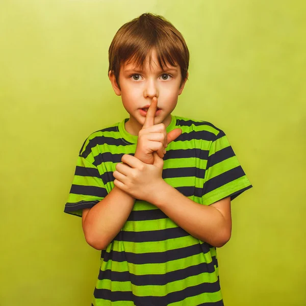 Teenager boy holding finger to his mouth silence requested quiet Stock Picture