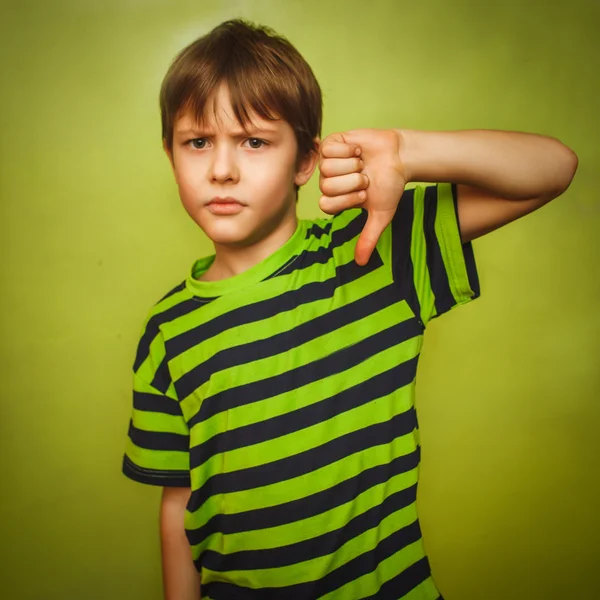 Мальчик подросток показывает большие пальцы вниз на большой зеленой backgroun — стоковое фото