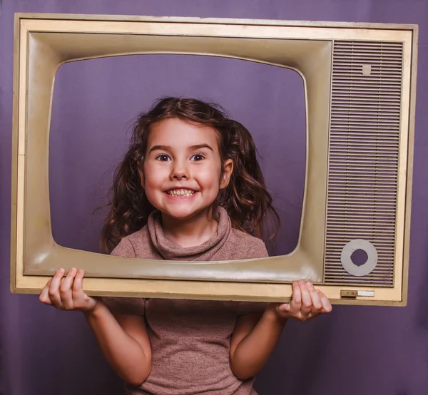 Дівчина-підліток дитина обрамлена телевізором, посміхаючись на сірому фоні — стокове фото