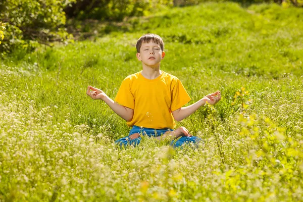 Rubia adolescente chico en una posición de loto meditando, meditación en na — Foto de Stock