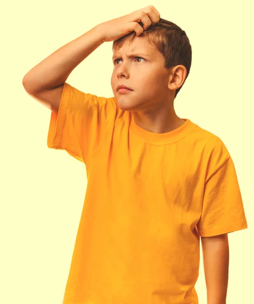 Chłopiec dziecko nastolatków blondynka w żółta koszulka drapanie jego głowę patrząc — Zdjęcie stockowe