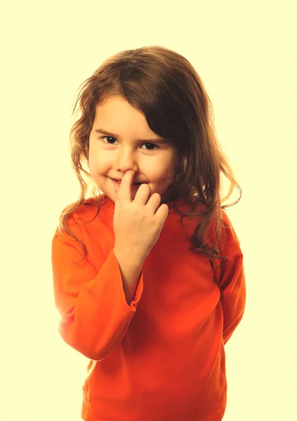 Kind krullend meisje in een oranje trui, het oppakken van zijn neus c — Stockfoto