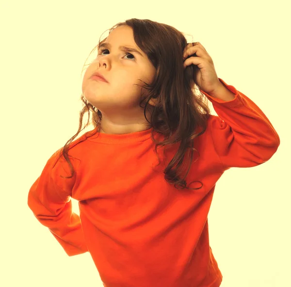 Portrait brunette kid orange sweater, scratching his head thinki — Stock Photo, Image